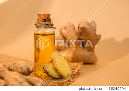 Glass bottle of essential ginger oil, ginger root on beige background. Healthy food eating concept. Zingiber officinale Essential oil. Natural cosmetics ingredients for skincare, body and hair care Glass bottle of essential ginger oil, ginger root on beige background. Healthy food eating concept. Zingiber officinale Essential oil. Natural cosmetics ingredients for skincare, body and hair care 86249294