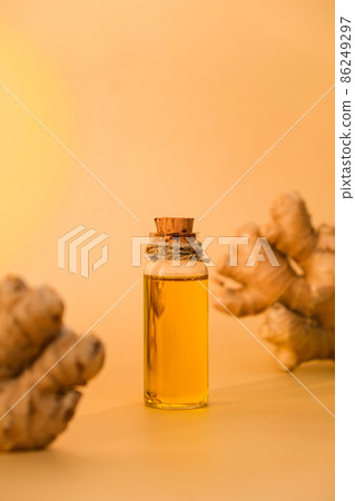 Glass bottle of essential ginger oil, ginger root on beige background. Healthy food eating concept. Zingiber officinale Essential oil. Natural cosmetics ingredients for skincare, body and hair care 86249297