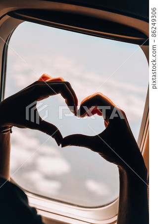 Female hand in heart shape View from the window of the plane. Airplane, Aircraft. Traveling by air. Vacation love travel concept Airplane Window View Above the Clouds Amazing golden fluffy clouds Female hand in heart shape View from the window of the plane. Airplane, Aircraft. Traveling by air. Vacation love travel concept Airplane Window View Above the Clouds Amazing golden fluffy clouds 86249306