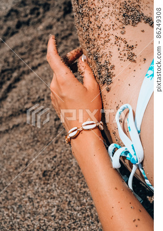 Woman's hands with shell jewelry in sand. Sand in hands on the beach. Travel and vacation concept. Female slim legs. Woman's hands with shell jewelry in sand. Sand in hands on the beach. Travel and vacation concept. Female slim legs. 86249308