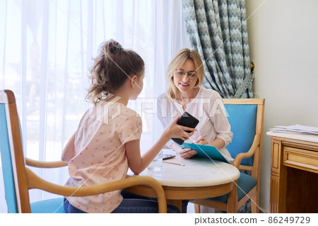 Woman teacher, therapist, social worker talking to preteen girl in office. 86249729