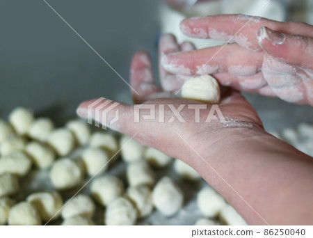 A woman sculpts Russian traditional ravioli dumplings. Hands twist balls of flour A woman sculpts Russian traditional ravioli dumplings. Hands twist balls of flour 86250040