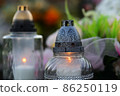 Concept of passing away - close up of burning candles on a grave as a memory of a deceased person. 86250119