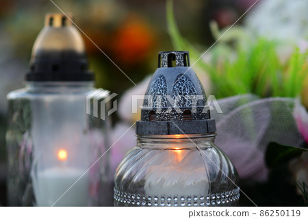 Concept of passing away - close up of burning candles on a grave as a memory of a deceased person. 86250119
