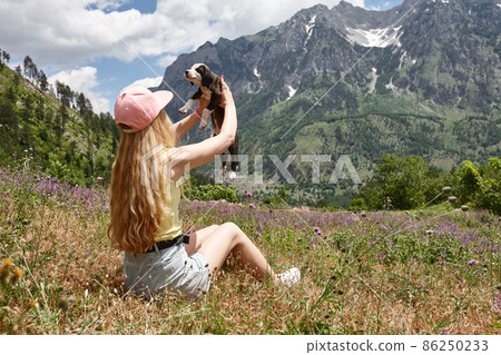 Young woman with puppy in beautiful mountains 86250233