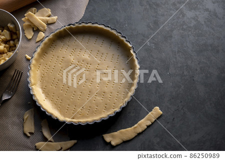 Homemade pie crust in pie plate. Cooking apple pie, dark background. Copy space Homemade pie crust in pie plate. Cooking apple pie, dark background. Copy space 86250989