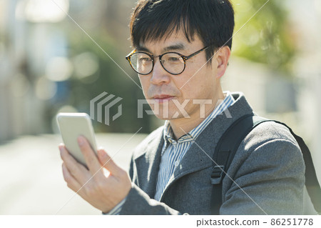 一個人在散步時看手機 一個人在散步時看手機 86251778