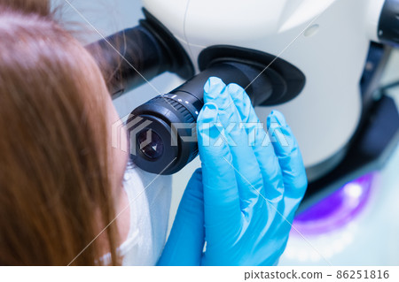 Professional female scientist doing experiment with electronic microscope in scientific genetic research laboratory 86251816