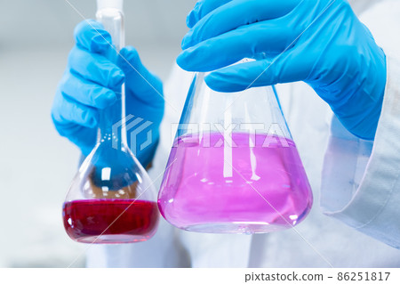 Scientist doing experiments with bright solutions in the flasks at the chemical laboratory. Researcher working in modern microbiology center. 86251817