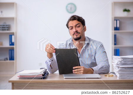 Young male employee unhappy with excessive work in the office 86252627