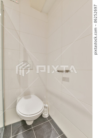 interior of a toilet room with white tiles on the wall and black ones on the floor 86252697