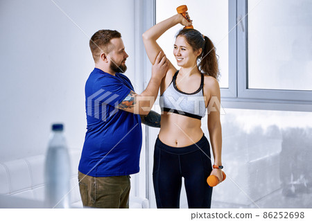 Training with coach using dumbbells by woman indoors. 86252698