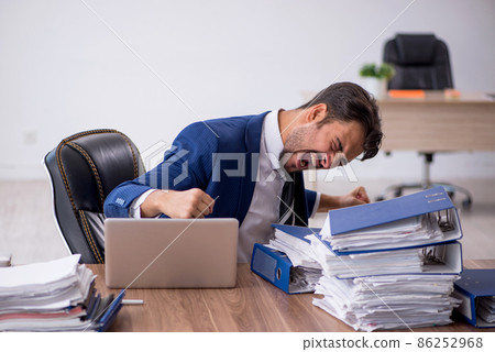 Young male employee and too much work in the office Young male employee and too much work in the office 86252968