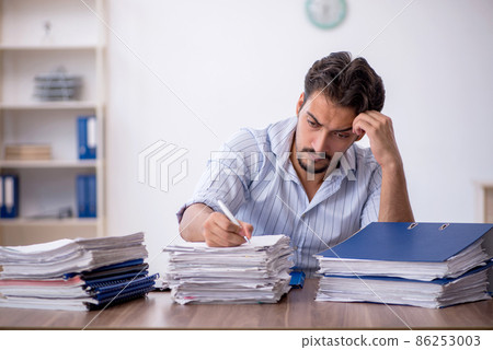 Young male employee and too much work in the office 86253003