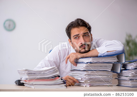 Young male employee and too much work in the office 86253100
