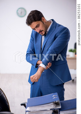 Young male employee and too much work in the office Young male employee and too much work in the office 86253101