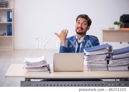 Young male employee and too much work in the office 86253103