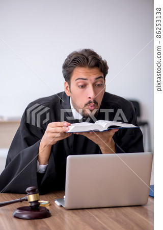Young male judge reading book in the courthouse 86253138