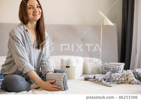 Spring cleaning of closet. Vertical tidying up storage. Neatly folded clothes in the metal white baskets for wardrobe. Nordic style. Spring cleaning of closet. Vertical tidying up storage. Neatly folded clothes in the metal white baskets for wardrobe. Nordic style. 86253306