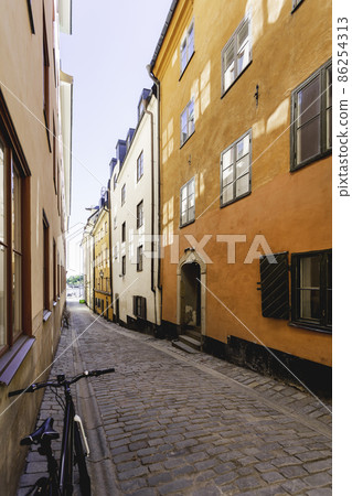 Bright sun reflections on narrow street in historic part of Stockholm. Old fashioned building in Gamla stan. Sweden. Bright sun reflections on narrow street in historic part of Stockholm. Old fashioned building in Gamla stan. Sweden. 86254313