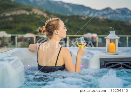 Portrait of young carefree happy smiling woman relaxing at hot tub during enjoying happy traveling moment vacation life against the background of green big mountains Portrait of young carefree happy smiling woman relaxing at hot tub during enjoying happy traveling moment vacation life against the background of green big mountains 86254540