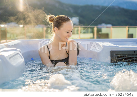 Portrait of young carefree happy smiling woman relaxing at hot tub during enjoying happy traveling moment vacation life against the background of green big mountains Portrait of young carefree happy smiling woman relaxing at hot tub during enjoying happy traveling moment vacation life against the background of green big mountains 86254542