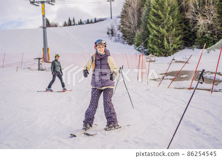 Woman learning to ski. Young woman skiing on a snowy road in the mountains 86254545