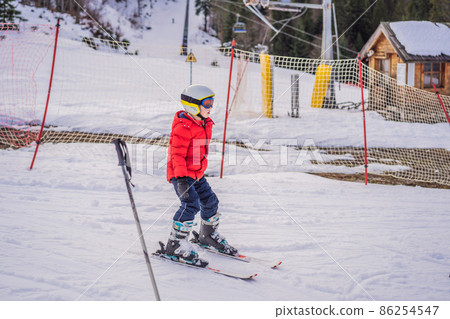 Child skiing in mountains. Active toddler kid with safety helmet, goggles and poles. Ski race for young children. Winter sport for family. Kids ski lesson in alpine school. Little skier racing in snow Child skiing in mountains. Active toddler kid with safety helmet, goggles and poles. Ski race for young children. Winter sport for family. Kids ski lesson in alpine school. Little skier racing in snow 86254547