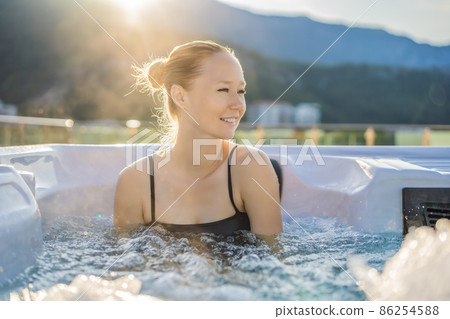 Portrait of young carefree happy smiling woman relaxing at hot tub during enjoying happy traveling moment vacation life against the background of green big mountains 86254588