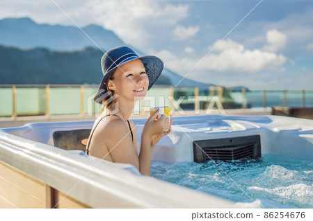 Portrait of young carefree happy smiling woman relaxing at hot tub during enjoying happy traveling moment vacation life against the background of green big mountains Portrait of young carefree happy smiling woman relaxing at hot tub during enjoying happy traveling moment vacation life against the background of green big mountains 86254676