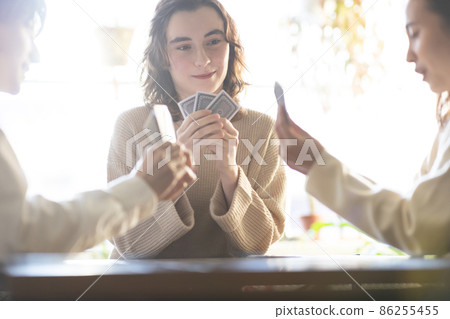 Young men and women enjoying playing cards Young men and women enjoying playing cards 86255455