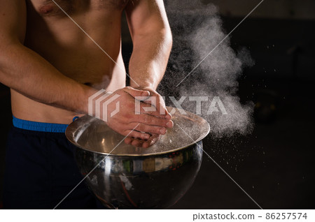 Caucasian man with naked torso uses talcum powder in the gym.  86257574