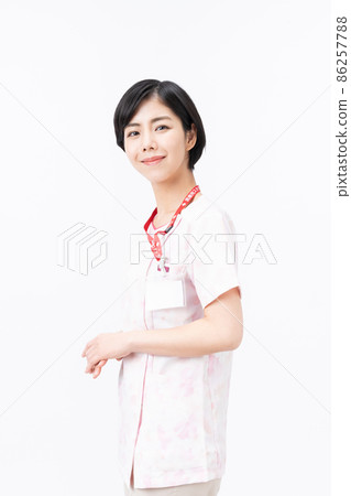 Young female nurse in pink floral scrub (white background) 86257788