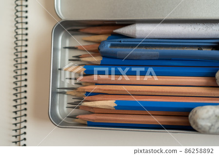 一個鉛筆盒，裡面有一支繪圖鉛筆、一個玉米餅、一根橡皮筋和一把美工刀。 86258892