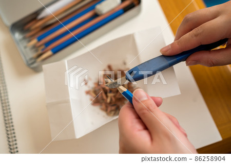 Sharpen a drawing pencil with a utility knife 86258904