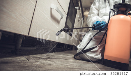 Spray gun with pesticides close-up. An exterminator in work clothes sprays pesticides from a spray bottle. Fight against insects in apartments and houses. Disinsection of premises Spray gun with pesticides close-up. An exterminator in work clothes sprays pesticides from a spray bottle. Fight against insects in apartments and houses. Disinsection of premises 86261517