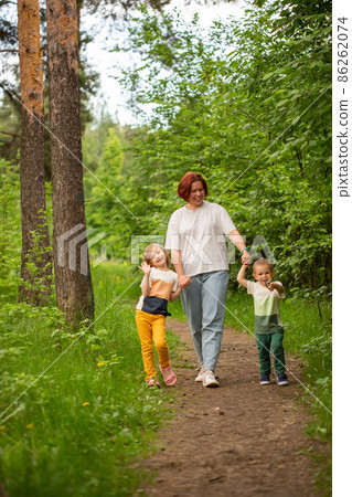 Mom walks with two children in the summer in the forest 86262074