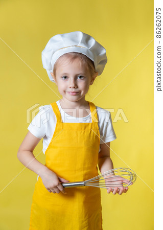 Girl in apron and chef's hat holding a whisk for whipping cream 86262075