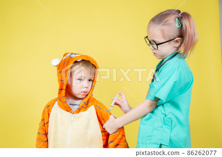 girl dressed as a doctor gives an injection to a boy dressed as a tiger 86262077