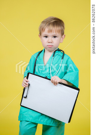 Portrait of little kid dressed in doctors green coat holds tablet in hand 86262078