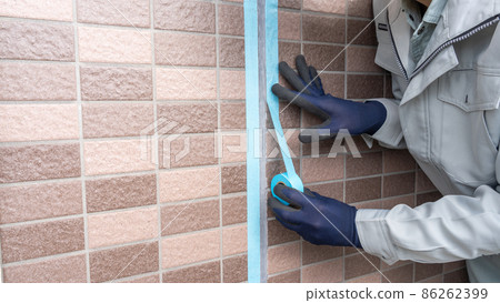 Exterior wall construction | Workers who cure the area around the joints with masking tape Exterior wall construction | Workers who cure the area around the joints with masking tape 86262399