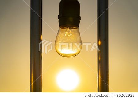 A light bulb that shines in the setting sun 86262925