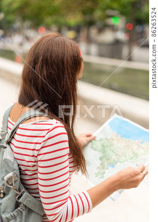 Anonymous woman with backpack and map in city 86263524