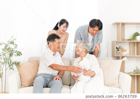 An old couple holding a baby and a young couple (homecoming) An old couple holding a baby and a young couple (homecoming) 86263789