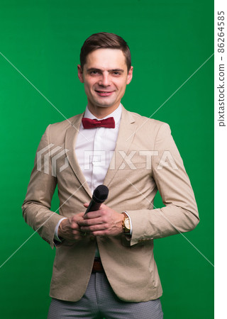 Portrait of professional male reporter holding a microphone, isolated on white and green background Portrait of professional male reporter holding a microphone, isolated on white and green background 86264585