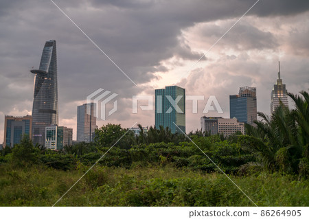 Picture of skyscrapers at sunset in the park with green grass and trees. View in metropolis with modern buildings. High quality photo Picture of skyscrapers at sunset in the park with green grass and trees. View in metropolis with modern buildings. High quality photo 86264905