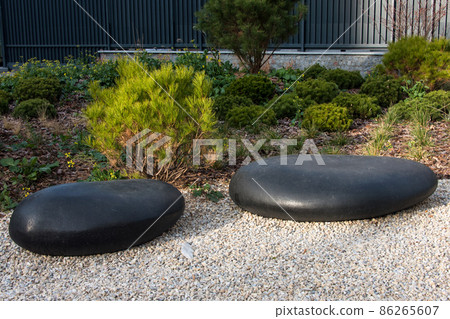 Zen garden dry landscape, or karesansui, japanese rock garden with black stones on white gravel for relaxation and concentration during meditation. Traditional Japanese temple settings 86265607