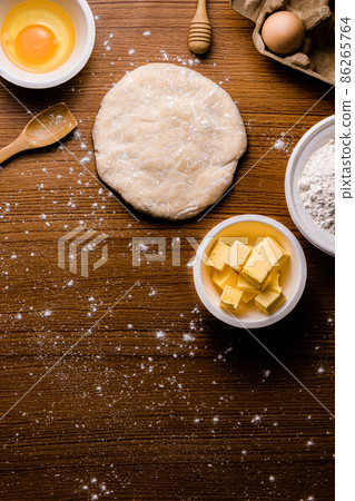 bread concept a bun dough, a tiny wooden spatula, a bowl of flour and a bowl of a raw egg organized on the wooden scene bread concept a bun dough, a tiny wooden spatula, a bowl of flour and a bowl of a raw egg organized on the wooden scene 86265764