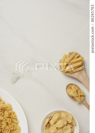 pasta concept some types of pasta being organized on wooden spoons while some being put on white background pasta concept some types of pasta being organized on wooden spoons while some being put on white background 86265765