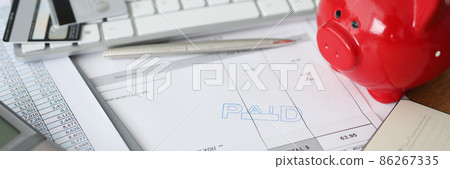 Invoice with paid stamp with bank cards and piggy bank on table Invoice with paid stamp with bank cards and piggy bank on table 86267335